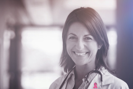 Breast cancer awareness ribbon against portrait of smiling female doctorの写真素材