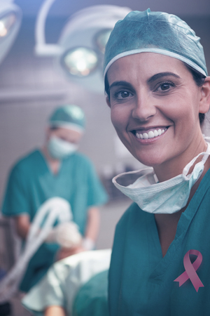 Breast cancer awareness ribbon against woman surgeon smilingの写真素材