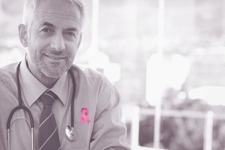 Breast cancer awareness ribbon against portrait of smiling doctorの写真素材