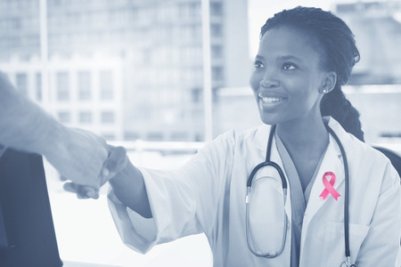 Breast cancer awareness ribbon against female doctor shaking handの写真素材