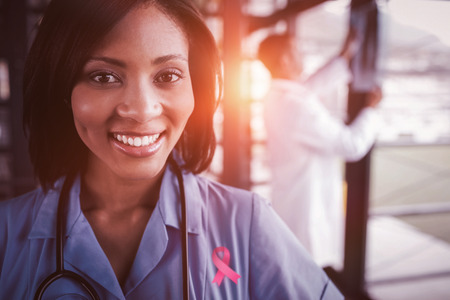 Breast cancer awareness ribbon against portrait of smiling nurseの写真素材