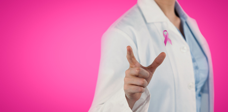 Midsection of female doctor using digital screen against pink backgroundの写真素材