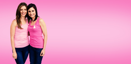 Smiling women in pink outfits posing for breast cancer awareness against pinkの写真素材