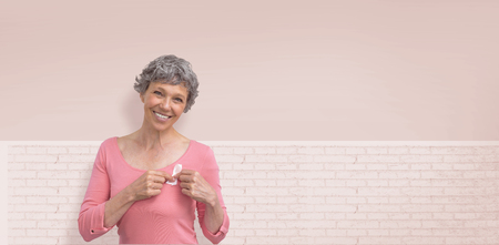 Woman in pink outfits showing ribbon for breast cancer awareness against white wallの写真素材