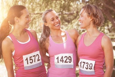Smiling women running for breast cancer awareness on a sunny dayの写真素材