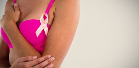 Mid section of woman in pink bra with ribbon against gray backgroundの写真素材