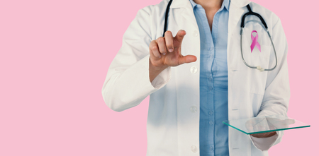 Cropped image of female doctor holding digital tablet while using invisible screen against pink backgroundの写真素材