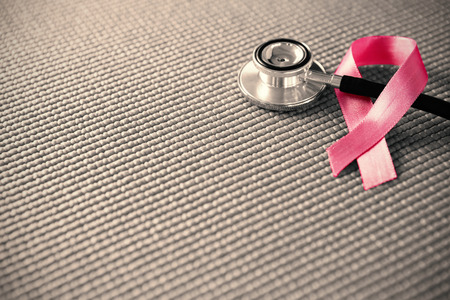High angle view of pink Breast Cancer Awareness ribbon with stethoscope on fabricの写真素材