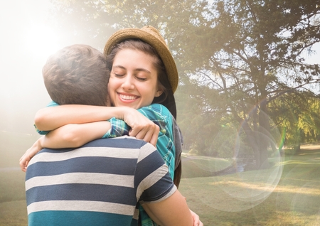 Digital composite of Couple hugging in blurry park with flaresの写真素材