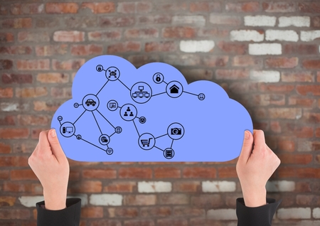 Digital composite of hands with cloud and application icons on it in front of a brick wallの写真素材