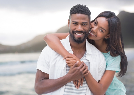 Digital composite of Couple embracing against blurry coastlineの写真素材