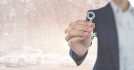 Digital composite of Hand  Holding key in front of street roadの写真素材