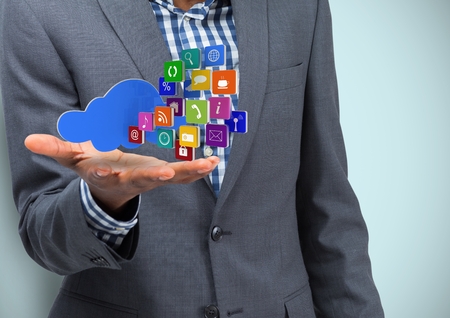 Digital composite of Business hand spread of with cloud and application icons. Light blue background