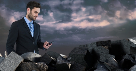 Digital composite of Dark bricks in pile with businessman holding phoneの写真素材