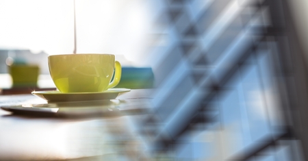 Digital composite of Green coffee cup on desk and blurry window transitionの写真素材