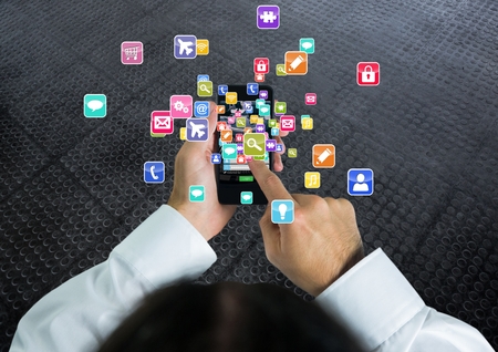 Digital composite of Man with phone on  hands and applications icons coming up from itの写真素材