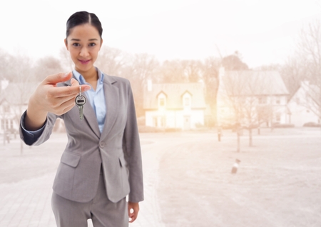 Digital composite of Woman Holding keys in front of housesの写真素材