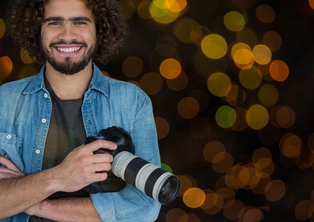 Digital composite of happy photographer with camera on hands. Orange and green bokeh background and overlap.の写真素材