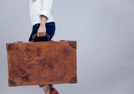 Digital composite of Millennial woman lower body with briefcase against grey wallの写真素材