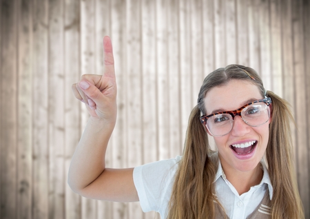 Digital composite of Nerd woman pointing up against blurry wood panelの写真素材