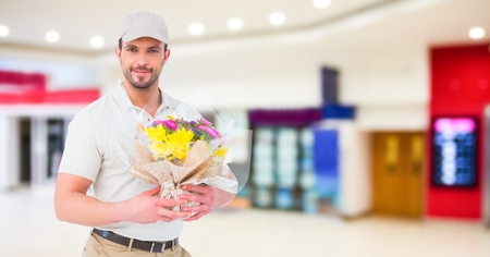Digital composite of Delivery man with flowers against blurry shopping centreの写真素材