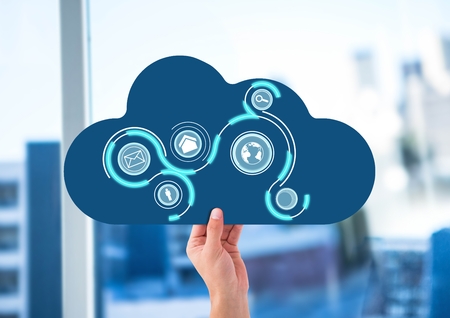 Digital composite of hand with cloud and application icons on it in front of the office window