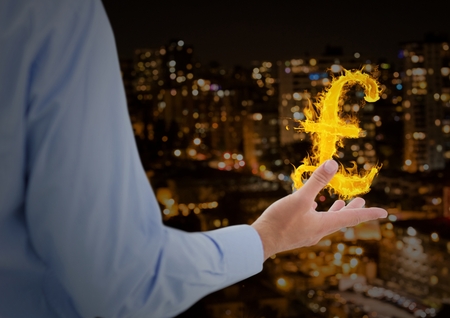 Digital composite of hand with pounds  fire icon over in front of the city at nightの写真素材