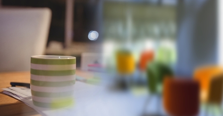Digital composite of Green and white coffee cup on desk and blurry office transitionの写真素材