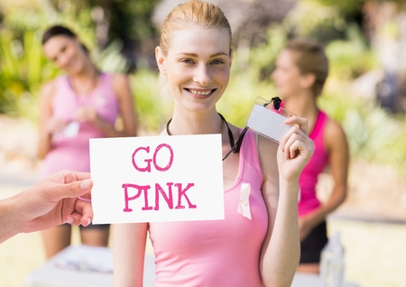 Digital composite of Go Pink Text and Hand holding card with pink breast cancer awareness womenの写真素材