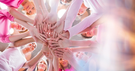 Digital composite of Hands together in circle with bright lightsの写真素材