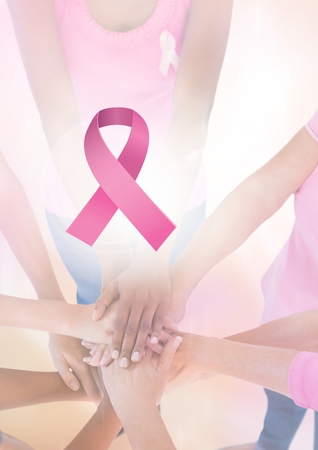 Digital composite of Pink ribbon with breast cancer awareness women putting hands togetherの写真素材