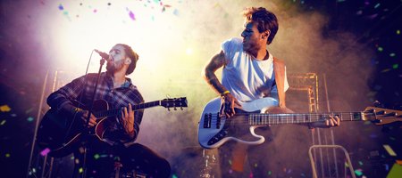 Flying colours against male guitarists performing on stageの写真素材