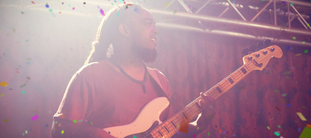 Flying colours against male guitarist playing guitar on stageの写真素材