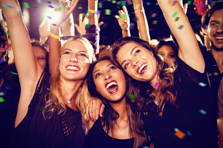 Flying colours against cheerful female friends enjoying at music festival