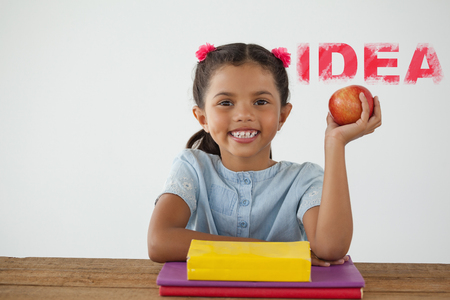 Digital composite image of pink idea text against schoolgirl holding a red apple against white backgroundの写真素材
