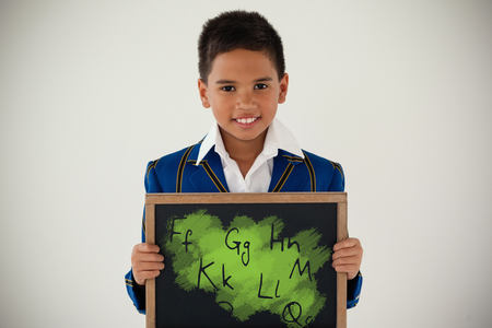 Graphic image of letters against schoolboy holding blank writing slate against white backgroundの写真素材