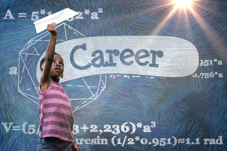 Boy holding paper airplane against career against black backgroundの写真素材