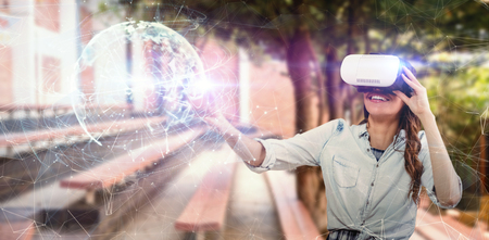 Happy young woman gesturing while using virtual reality simulator against global technology...