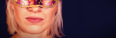 Close-up portrait of woman in masquerade mask against black backgroundの写真素材
