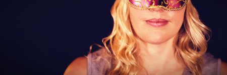 Portrait of young woman in masquerade mask against black backgroundの写真素材