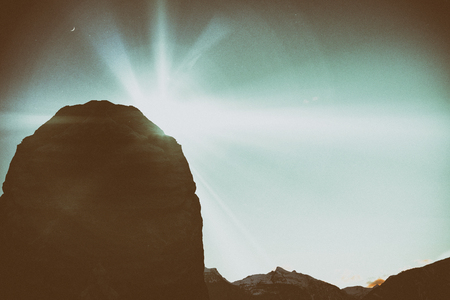 Cropped image of rocky mountain against snowcapped mountains against skyの写真素材