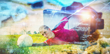 Goalkeeper in red making a save  against virtual reality headset on deskの写真素材