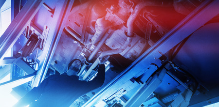 Mechanic watching under a car in garageの写真素材