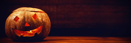 Illuminated jack o lantern on wooden table during Halloweenの写真素材