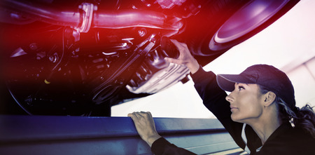 Mechanic girl watching under a car with a capの写真素材