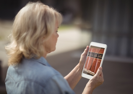 Digital composite of woman using bookshelf on tablet screenの写真素材