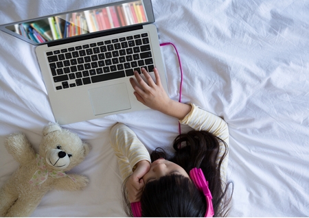 Digital composite of kid using bookshelf on laptop screenの写真素材