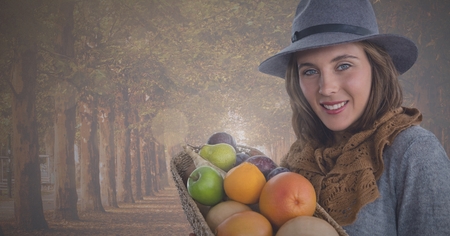 Digital composite of WOman holding fruit basket in Autumn in forestの写真素材