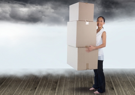 Digital composite of Businesswoman holding boxes with cloudsの写真素材