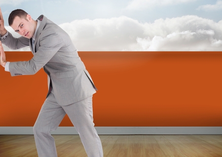Digital composite of Businessman with orange wall pushingの写真素材